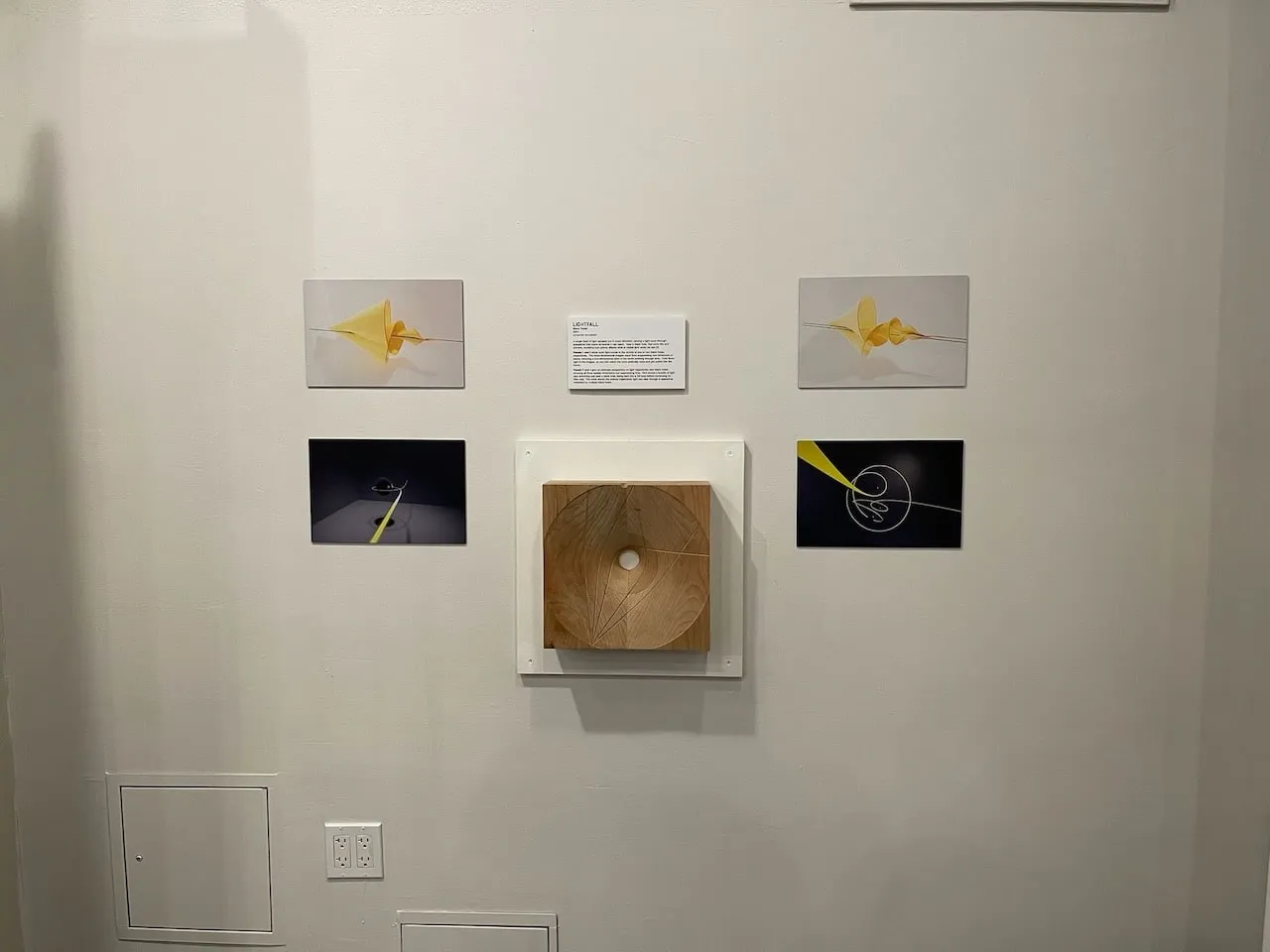 Lightfall wall display: wooden Geodesic Block at centre flanked by four photographs showing a yellow light ray bending around a curved surface