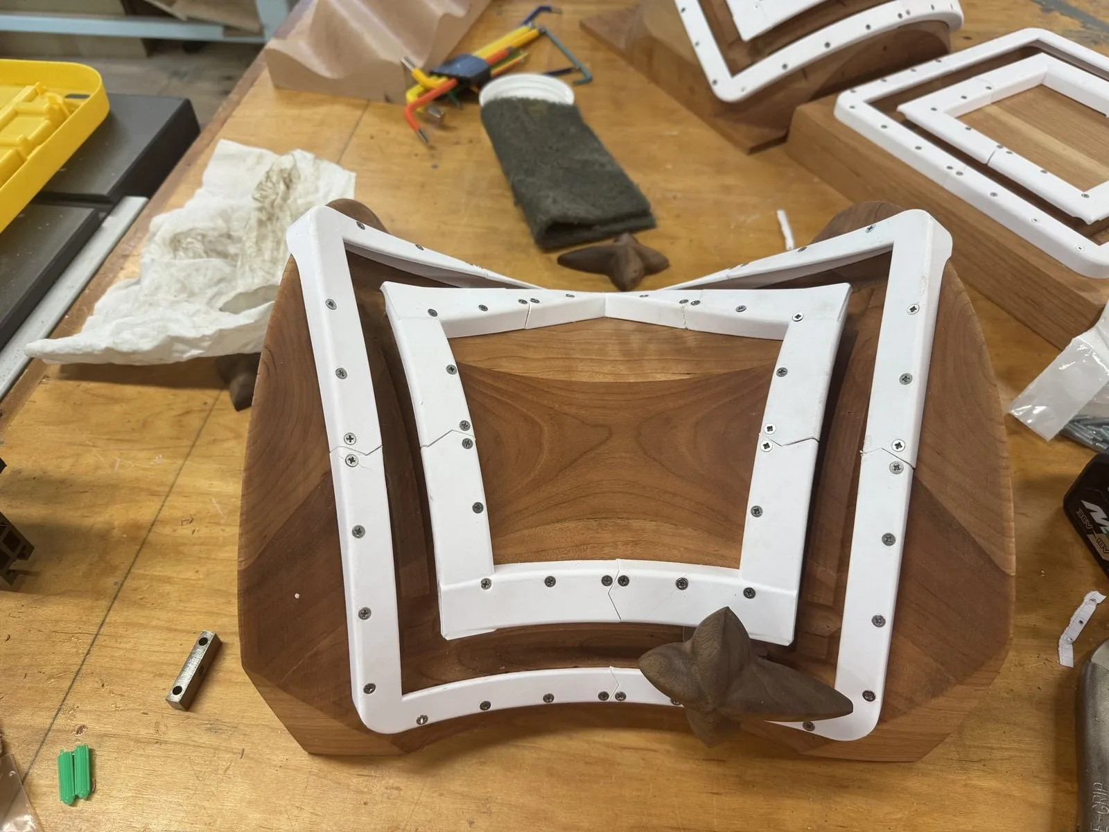 The saddle board on the workbench with white metal track frames being fitted