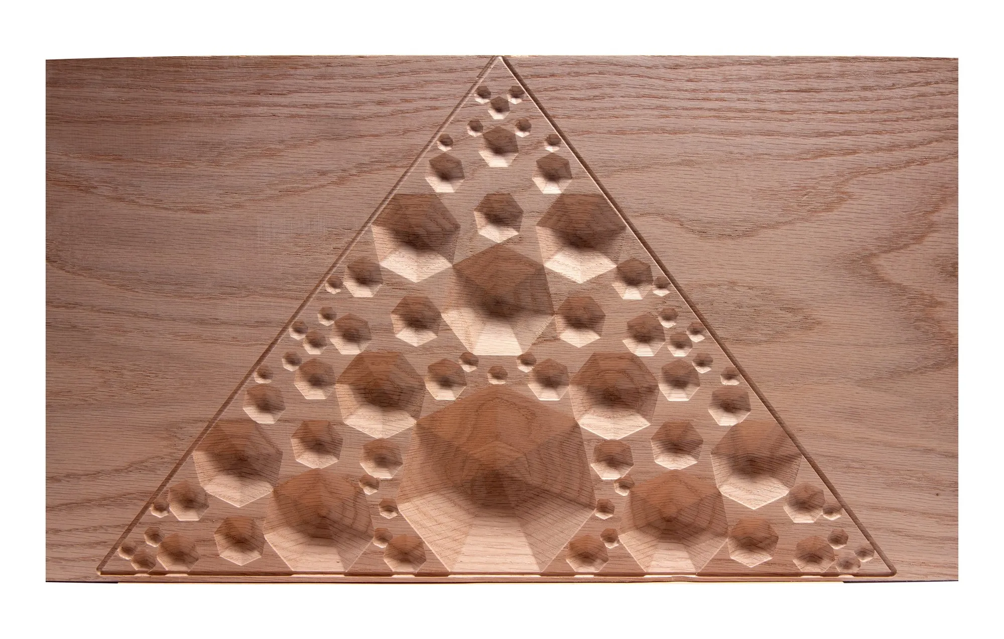 Professional studio shot of the Apollonian gasket oak triangle panel; concentric inscribed spheres carved in relief in a triangular arrangement, the pattern repeating at every scale, on a white background