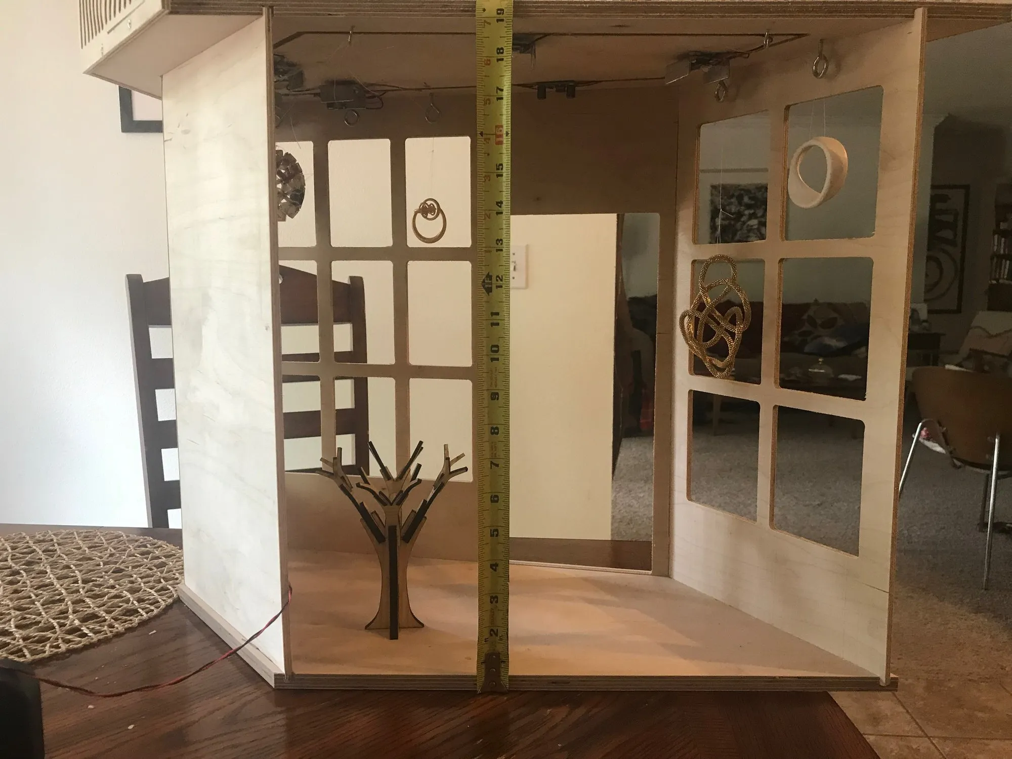 Conway's Curios shop interior open to the back, with a measuring tape showing roughly 18-inch height; laser-cut tree and a golden torus knot hanging in the windows, a small wreath at top