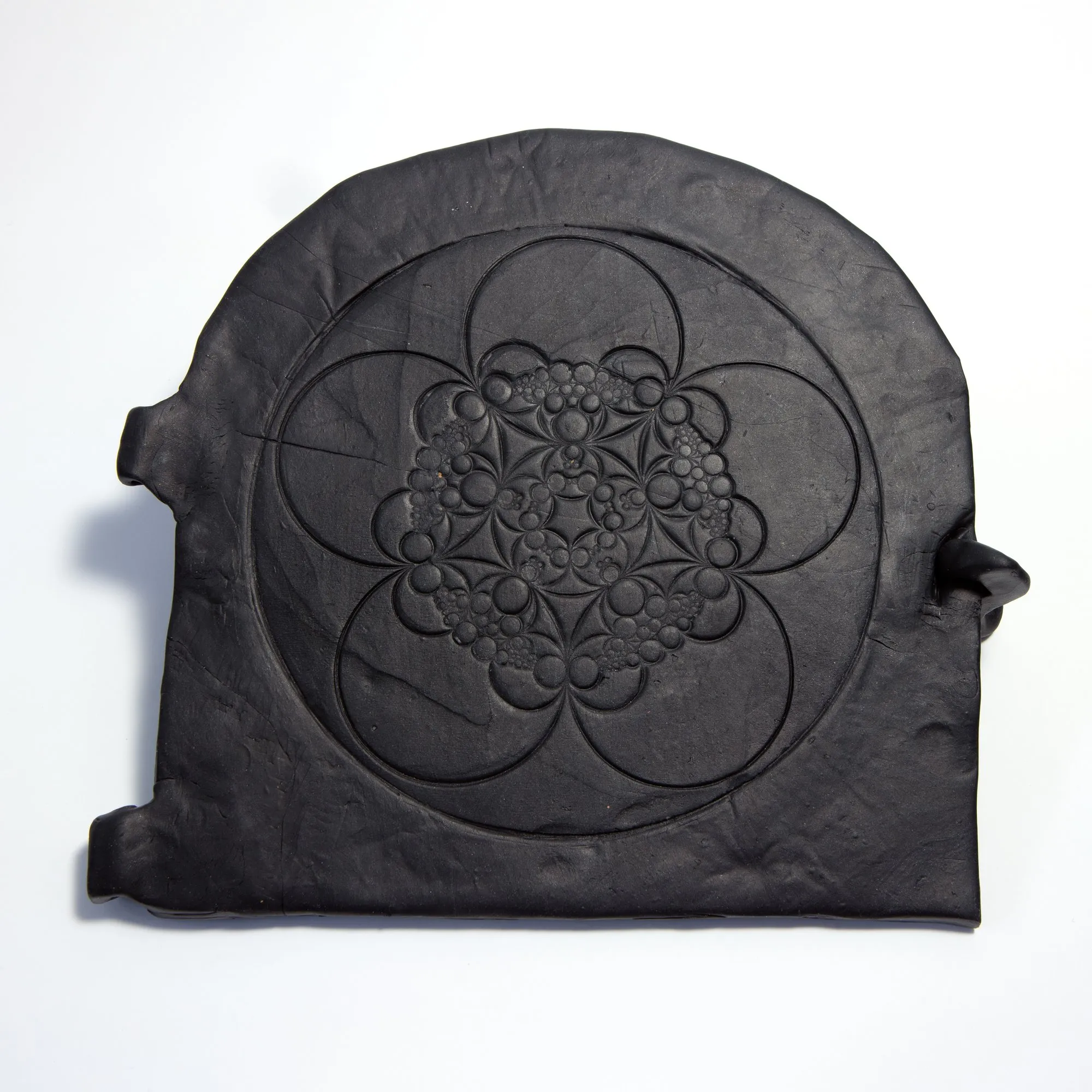 Professional studio shot of the Bakery oven door mould; a black rubber arched form with Apollonian circle-packing pattern and side mounting tabs, on a white background