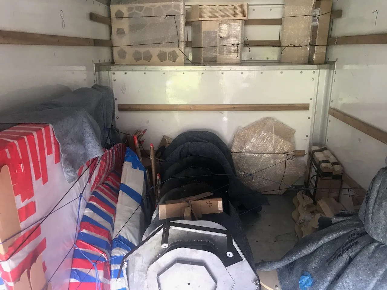 Interior of the loaded U-Haul truck for the drive to Duke; Voronoi floor hexagonal tiles stacked on the upper shelf wrapped in plastic, the black heptagonal base sections, Integral Hill contour layers, and packed installation elements below