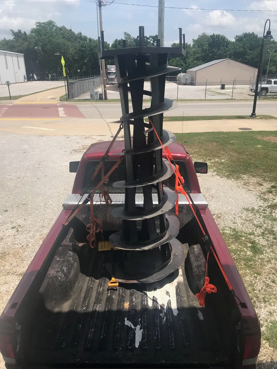 The Lighthouse tower in the red truck on the road trip to Duke; horizontal in the truck bed at a town intersection in bright sunlight, a collaborator visible at the wheel