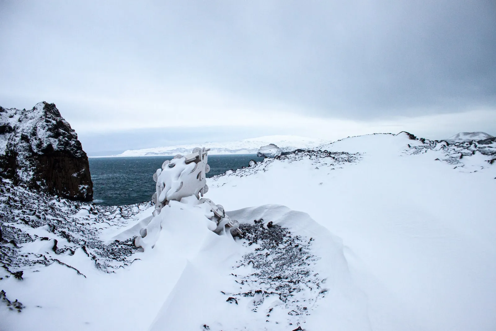 Sculpture System 5 on Heimaey in winter,  white sculpture, white snow, black lava, grey sea, December 2009