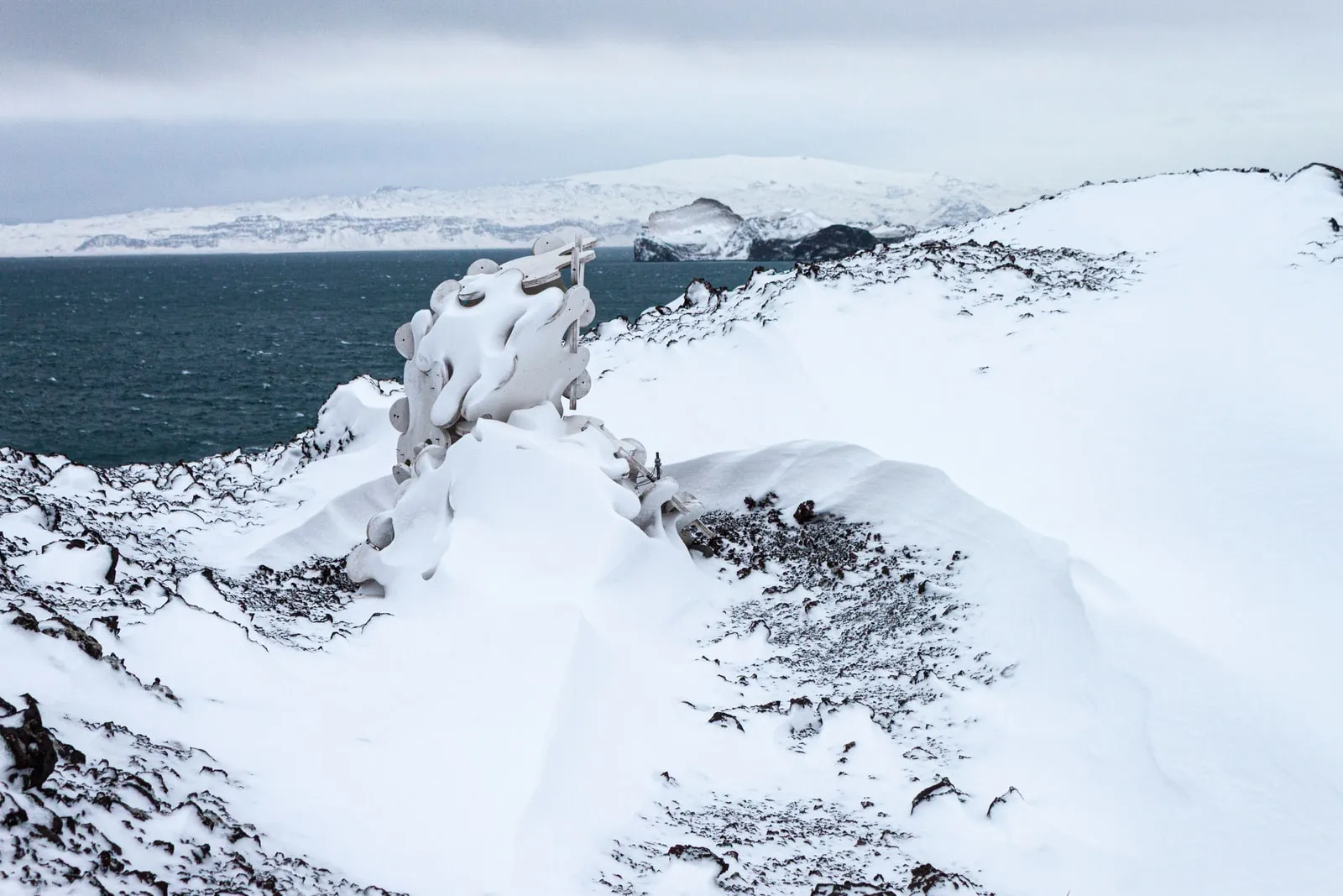 Sculpture System 5 in the Heimaey winter landscape,  small against the vast snow and sea, December 2009