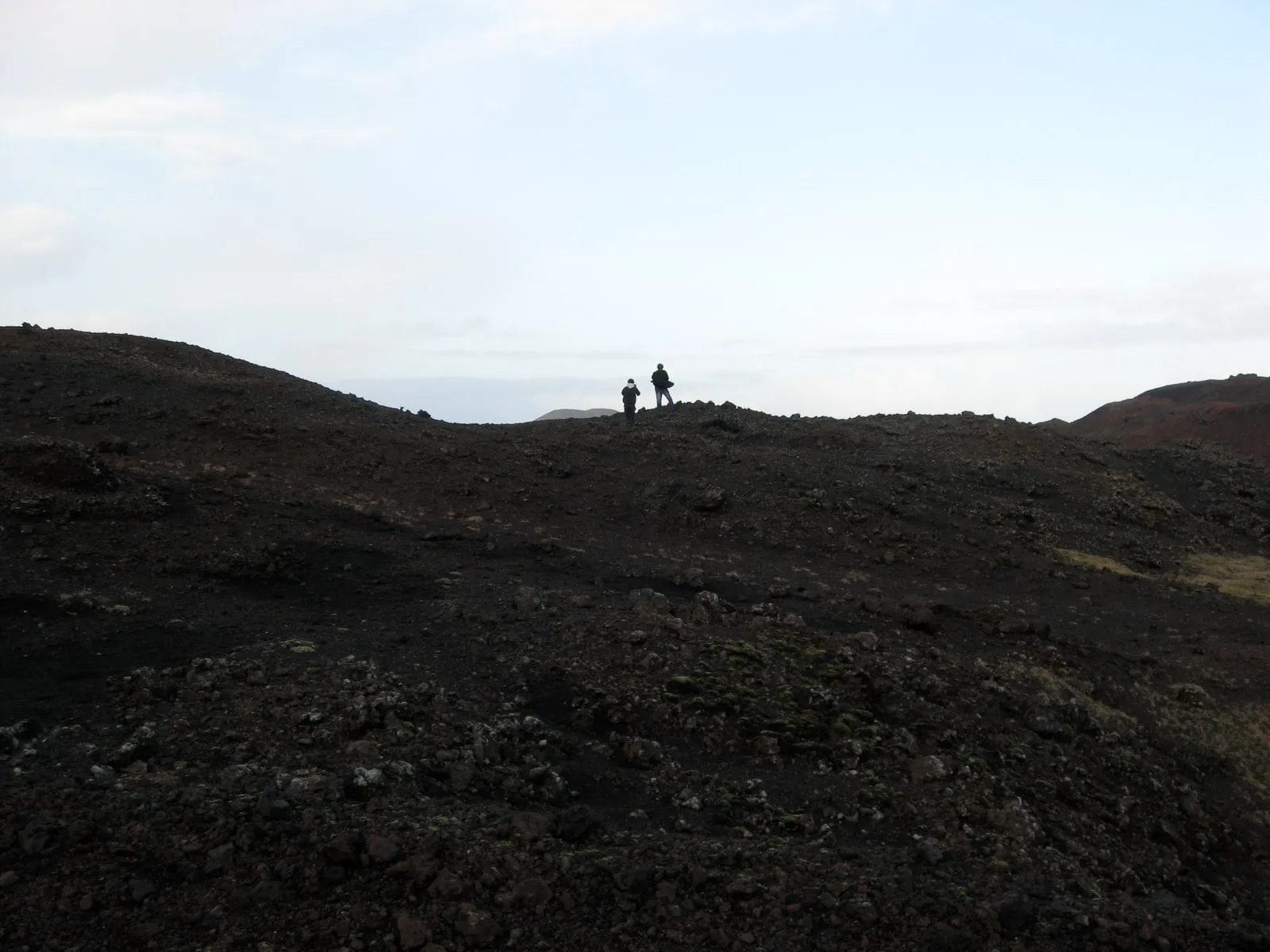 Two figures scouting the Eldfell lava field, the site where the sculpture will be installed