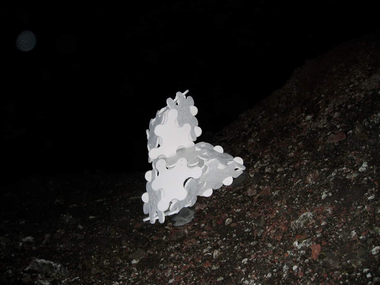 The completed sculpture tiny against the vast slope of the Eldfell lava field at night