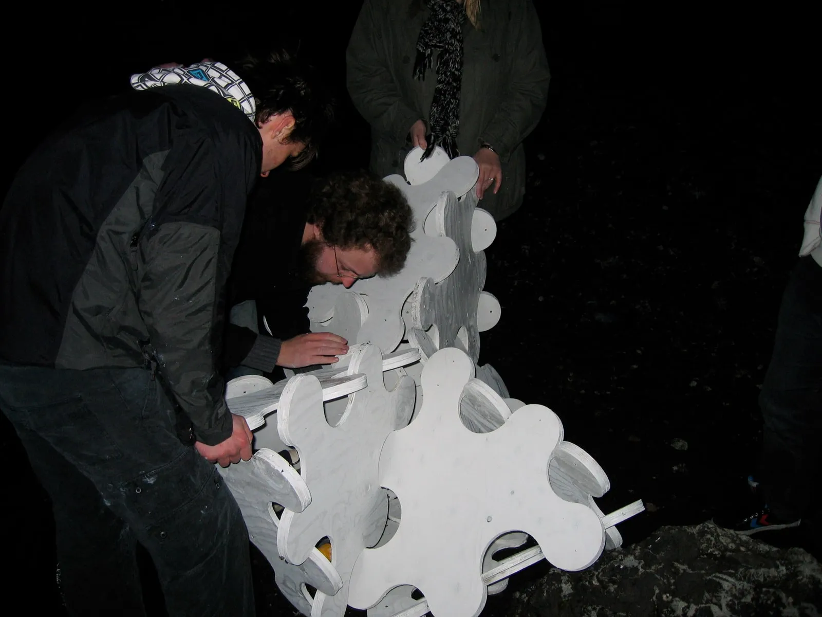 Sculpture System 5 rising from the lava field at dusk, the white form beginning to take shape in the dark