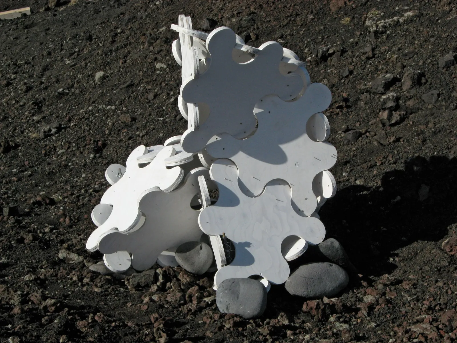 Sculpture System 5 resting low on the lava,  the interlocking hinge geometry visible